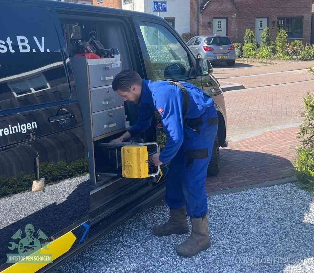 Een monteur pakt buiten op de oprit gereedschap uit de bedrijfsbus, het moment om een professional in te schakelen voor een verstopte afvoer in Schagen