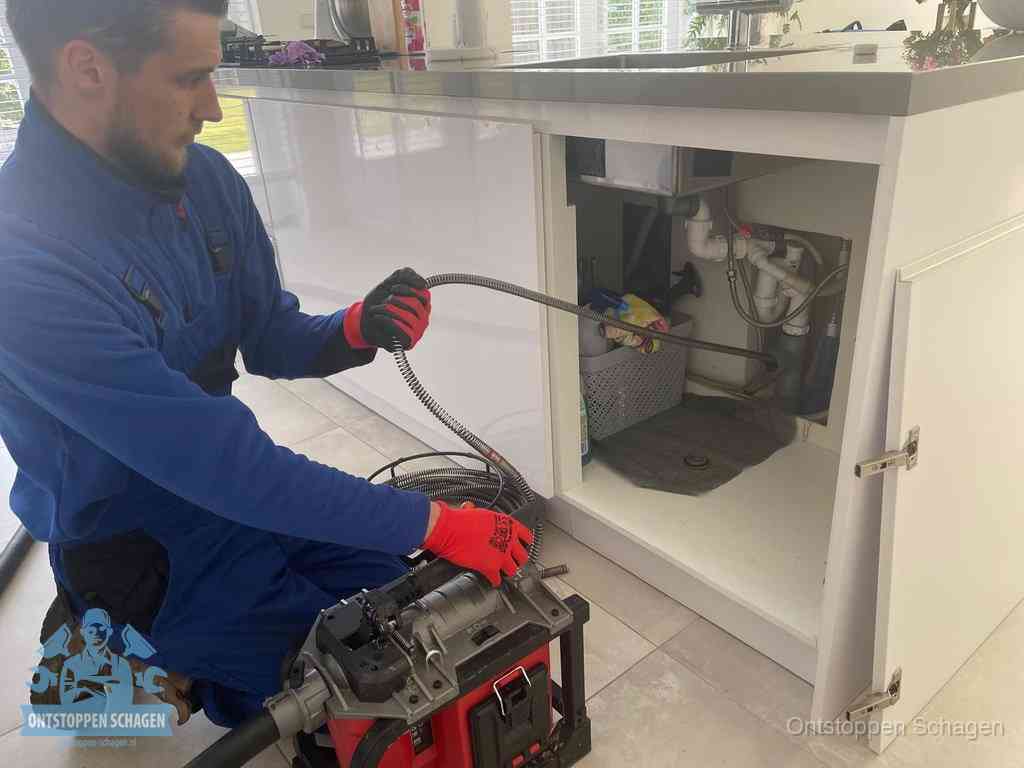 Een monteur reinigt de keukenafvoer grondig met een veermachine om terugkerende gootsteenverstoppingen te voorkomen in Schagen