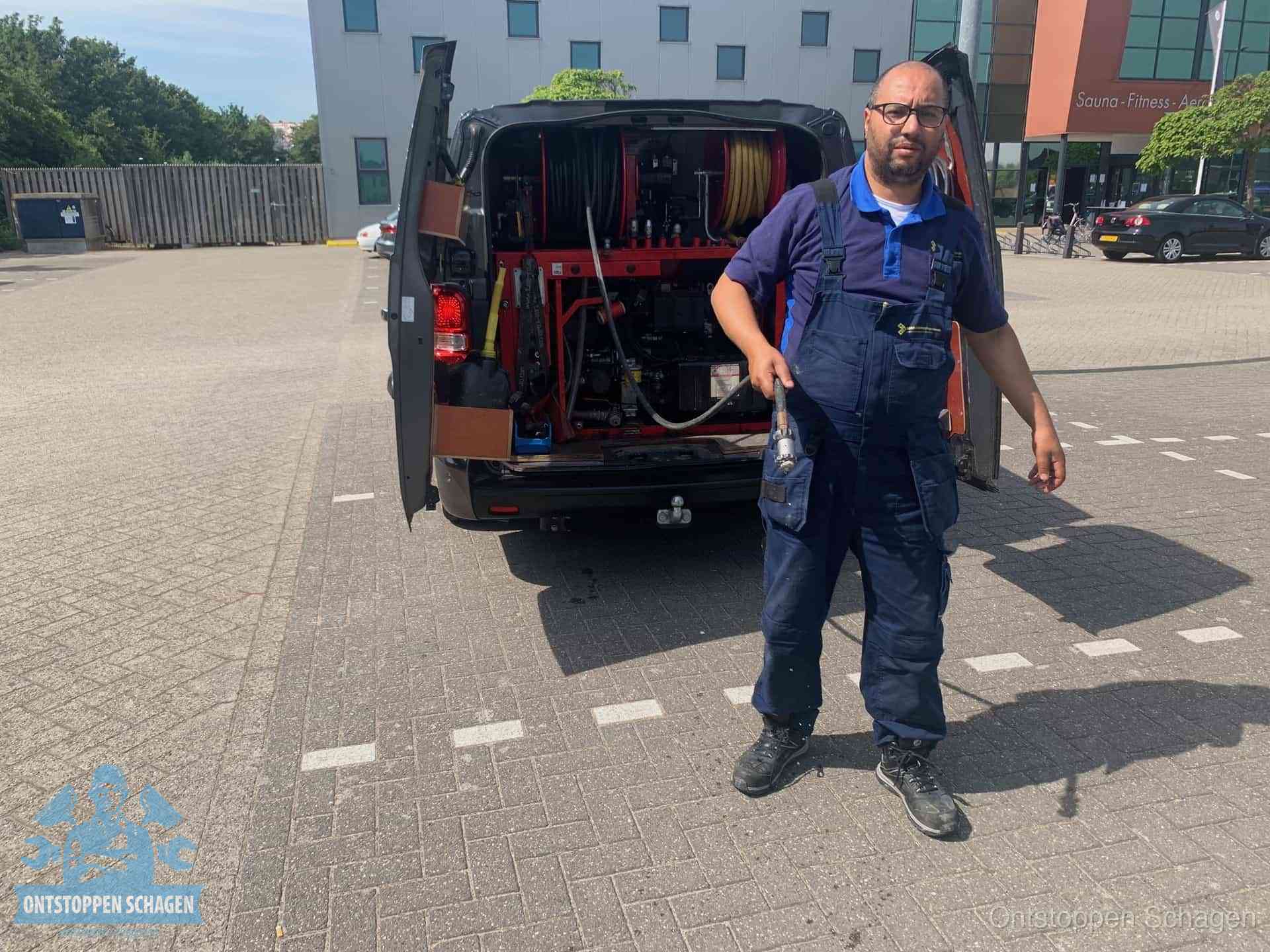 Een monteur bij zijn bestelbus met een hogedruk- en rioolreinigingsunit, klaar om de oorzaak van terugkerende wc-verstoppingen aan te pakken in Schagen